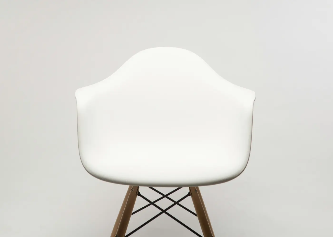 A white moulded armchair on slim wooden legs against a pale wall